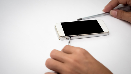 Man hand is repairing the smart phone on white background.の写真素材