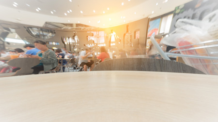 Wood table top with blurred people in a modern hall