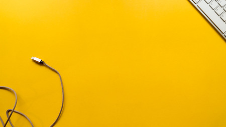 keyboard with Charger on yellow background business concept desk tableの写真素材