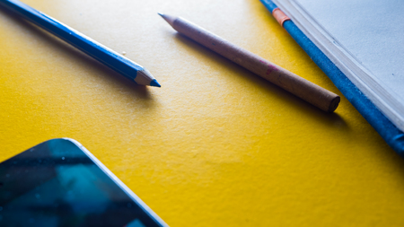 crayon color pencil close up and notebook with smartphone business conceptの写真素材