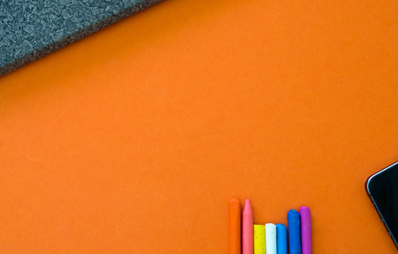 Notebook with crayon and smartphone on orange background copyspaceの写真素材