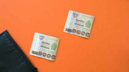 Black bag and bank thai bath on orange background.Money floating into the pocket creative concept