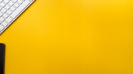 Keyboard with smartphone yellow background business concept desk table copyspaceの写真素材
