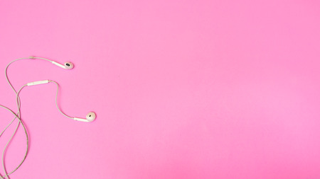 Top view of White Earphones on pink texture background. Pastel color concept, Minimal concept. Copy...