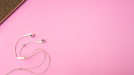 Earphones and notebook on pink  background. Pastel color Minimal concept Copy spaceの写真素材