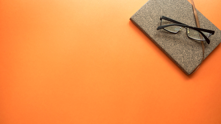 glasses  with notebook on orange backgroundの写真素材