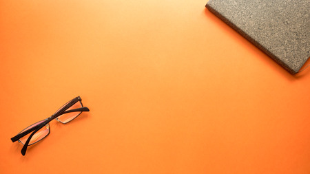 glasses  with notebook on orange backgroundの写真素材