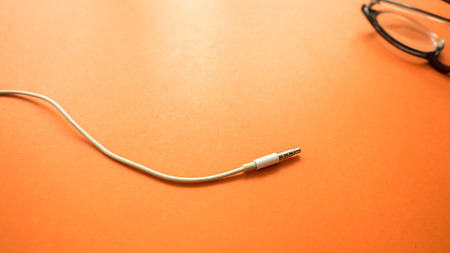 earphone with glasses close up on orange backgroundの写真素材