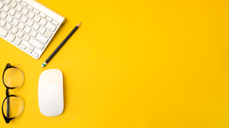 Office desk table Top view with keyboard copy space yellow backgroundの写真素材