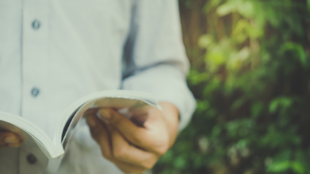 Man reading Book in his hands at gardenの写真素材