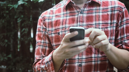 Young  hipster man working with smart phone outdoor with nature.