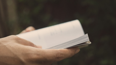 Man reading Book in his hands at garden