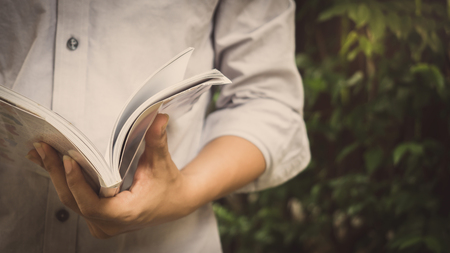 Man reading Book in his hands at gardenの写真素材