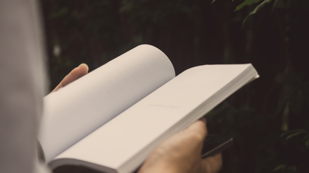 Man reading Book in his hands at gardenの写真素材