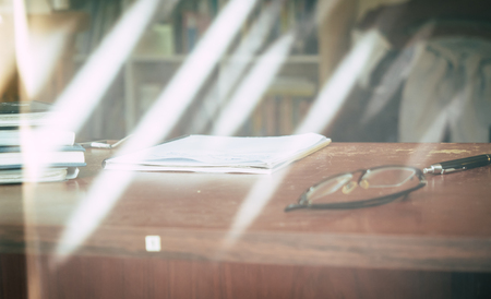 glasses with notebook on wood table at officeの写真素材