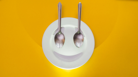 Plates and spoons sign symbol smile on yellow backgroundの写真素材