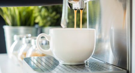 coffee machine espresso looking fresh coffee into a neat ceramic cupの写真素材