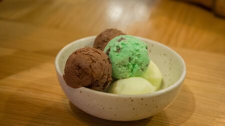 Ice cream in a white cup on a wooden tableの写真素材