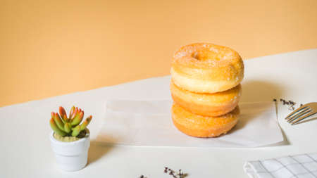 Homemade deep fried donuts in stack with sugar standing on crumpled paper with white table.の写真素材