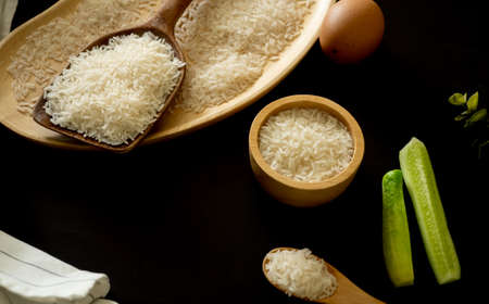 white rice (Thai Jasmine rice) in wooden bowl and unmilled rice isolated on black backgroundの写真素材