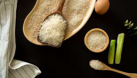 white rice (Thai Jasmine rice) in wooden bowl and unmilled rice isolated on black backgroundの写真素材