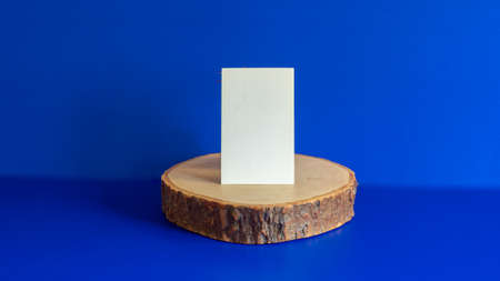 stationery mock-up scene. Blank white card, wooden plate, blue background . Feminine flat lay, top viewの写真素材