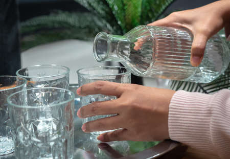 female hand pouring water into glassの写真素材