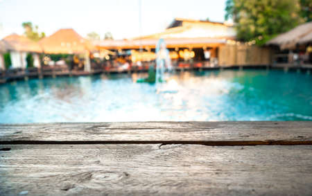 Image of wooden table in front of blurred background of pool and resturant.の写真素材