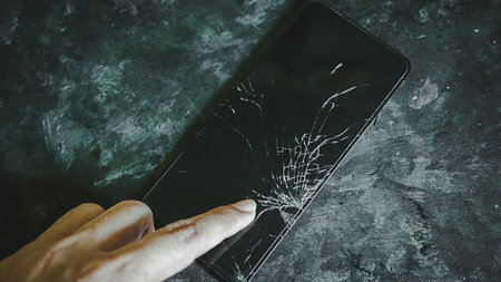 broken screen smarthphone on black background with fingerの写真素材