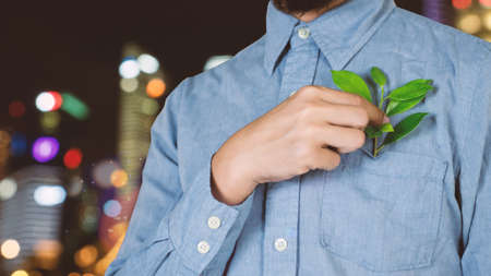 Hand holding a plant pot on a desk with a computer.business nature concept.