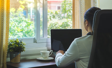 A business woman sits at a computer by the window near nature.business nature conceptの写真素材