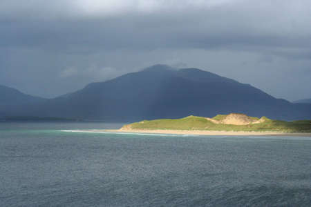 Looking towards a sunlit Luskentyre and the hills of North Harris from Seilebost on a showery day. Western Isles, Scotlandの写真素材
