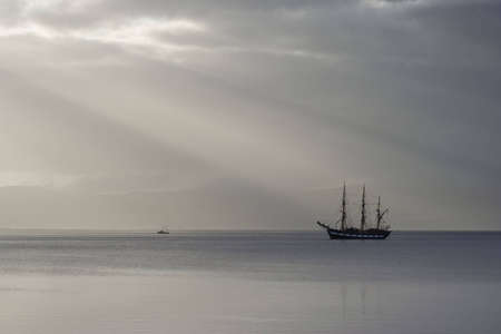 A tall ship lies at anchor in the morning sunlight in the Firth of Clyde near Buteの写真素材
