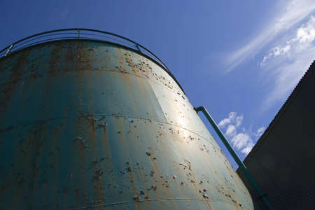 Peeling paint on an industrial tank against the skyの写真素材