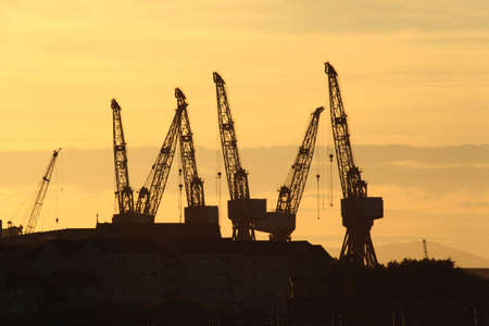 Shipbuilding cranes silhouetted against a Glasgow sunsetの写真素材