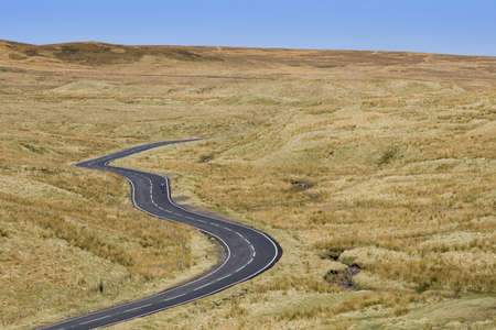 A lonely cyclist on an unfenced road winding across a Scottish moorの写真素材