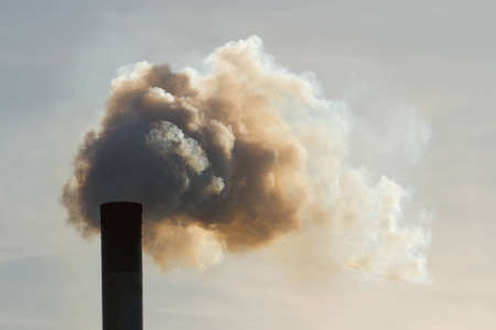 Fumes belch out of the top of an industrial chimneyの写真素材