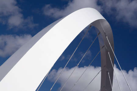 The supporting arch of the Clyde Arc bridge in Glasgow, Scotland, against blue sky and clouds