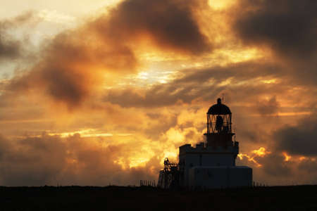 Birsay Lighthouse, Orkney, in silhouette at sunsetの写真素材