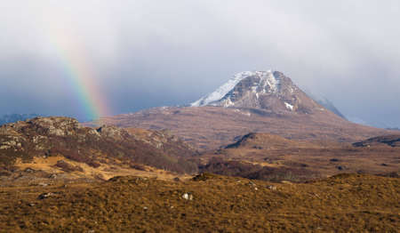 Sunshine creates a rainbow in a Scottish mountain landscapeの写真素材