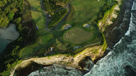 Drone footage of a group of people playing golf at a country club perched on a cliff by the ocean. Green golf course on the coast, people play golf.の写真素材