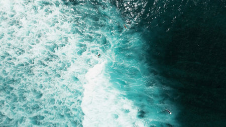 Surfers in the open ocean wait for a wave near Green Bowl Beach, Bali, Indonesiaの写真素材