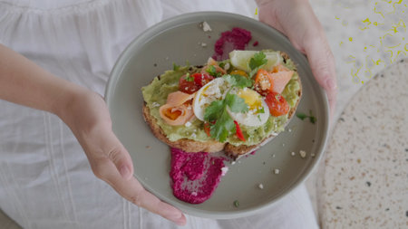 Healthy breakfast in a cafe, a young woman holds a plate with avocado toast.