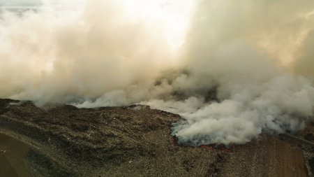 Aerial view of a catastrophic fire at a large landfill, plastic waste burning. Poisonous smoke rises...