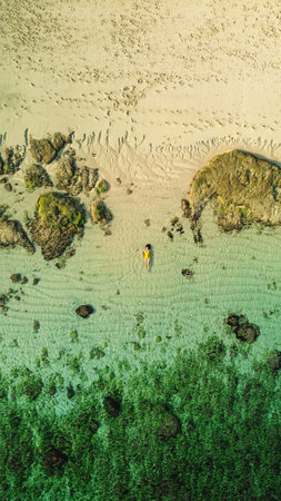 Top down view of a pregnant woman relaxing on the beach in a yellow swimsuit. Rest before childbirth in the third trimester of pregnancy. Beach holiday, young woman lying on the beach, drone view.の写真素材