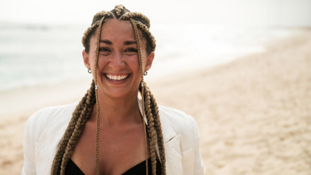 Portrait of a young Latino woman with braids who looks at the camera and smiles.