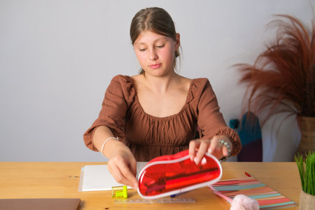 Teenage girl puts school supplies from the table and puts them in a pencil case to pack her backpack...