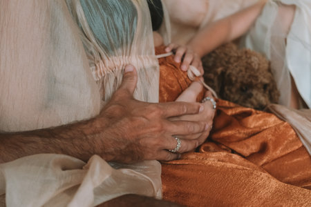 Family Christmas portrait. Pregnant woman with her husband and little daughter sitting on the sofa. They put their hands on her belly to feel the baby kicking. Magical holiday.の写真素材