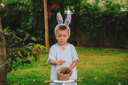 Festive Easter childrens game Egg hunt. The little boy search of eggs, collects them in a basket and...