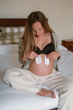 Portrait of a pregnant woman big belly, she puts little socks on her belly in anticipation of the...